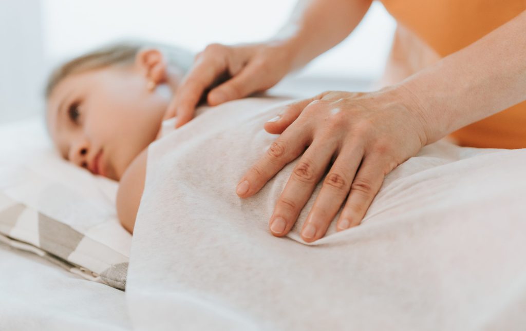 doctor osteopath hands does physiological and emotional therapy for eight year old kid girl. pediatric osteopathy treatment session. alternative medicine. taking care of the child's health